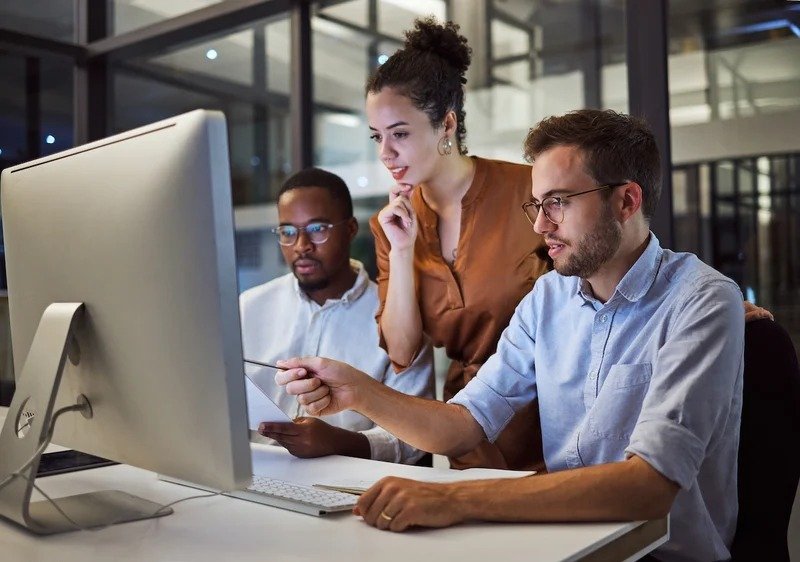 A dedicated marketing and operations team collaborating around a computer screen